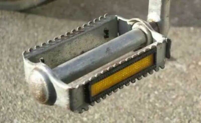 Vintage metal skateboard with a yellow grip tape and metal wheels.