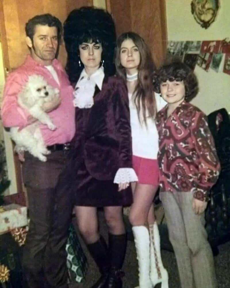 Family photo with four people and a dog, 1980s style clothing and hairstyles.