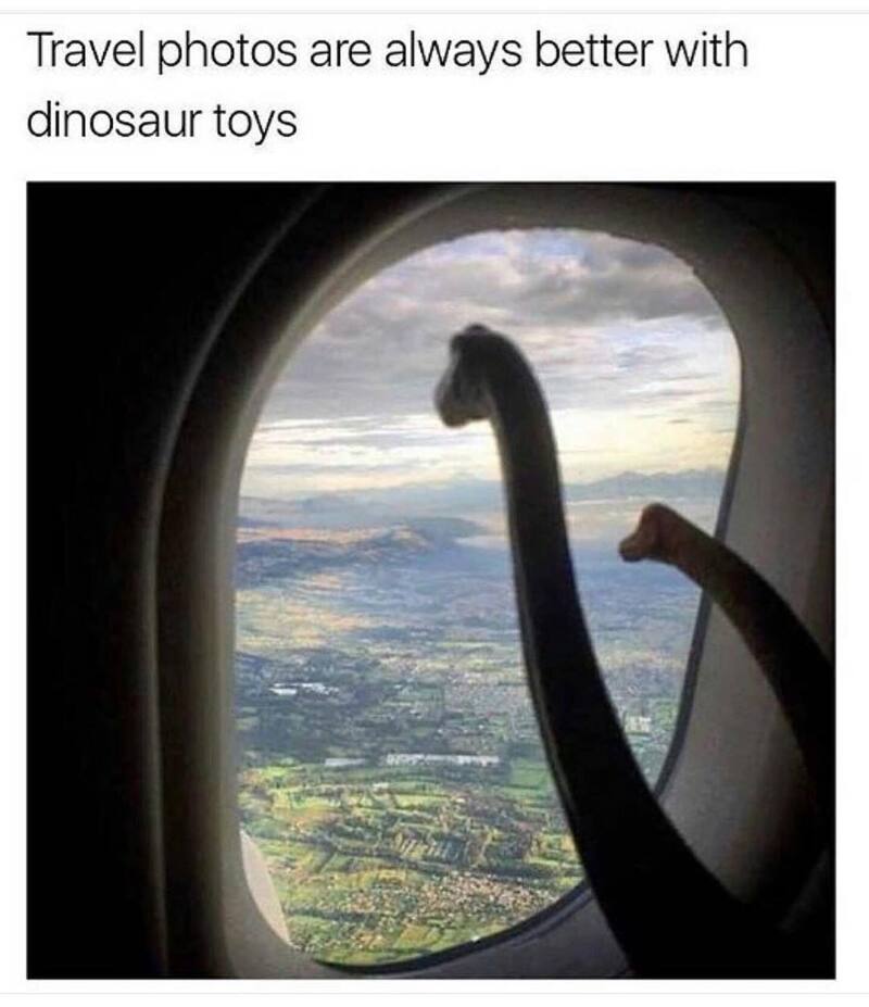 Dinosaur toys on airplane window with landscape view.