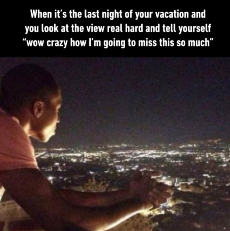 Person looking at city view at night with caption about missing vacation.