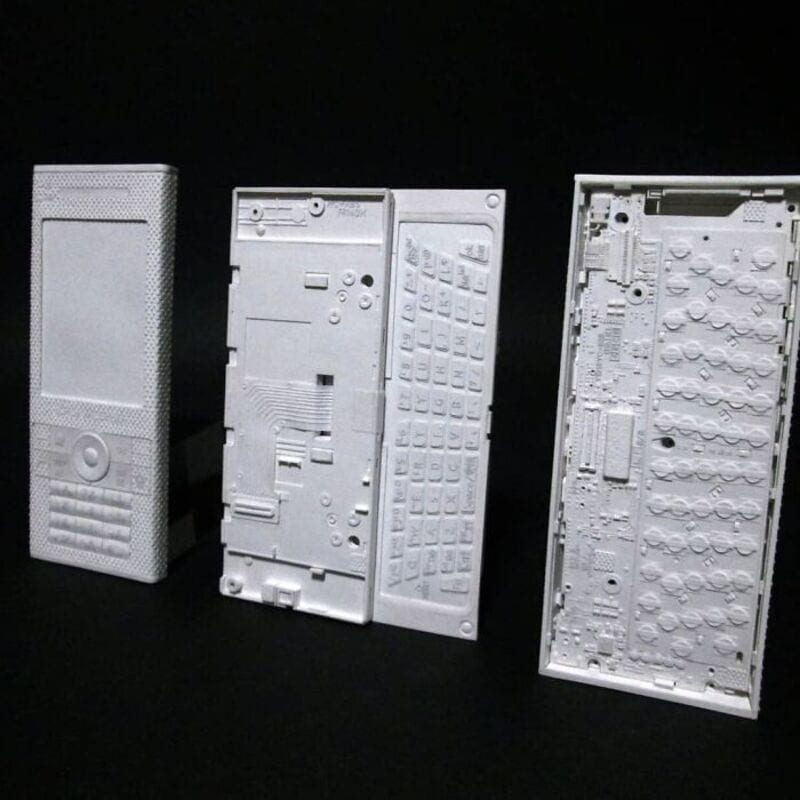 Three white paper sculptures of retro electronic devices on black background.