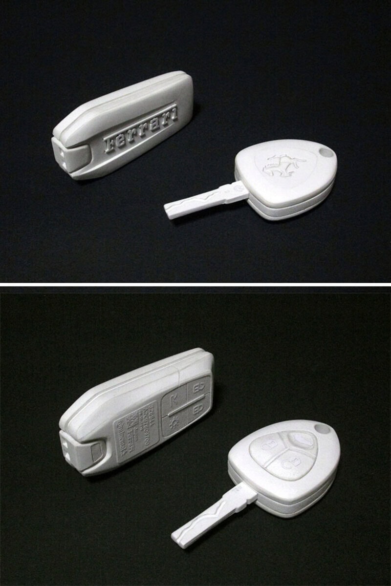 Two white car key fobs with embossed buttons and logos on a black background.