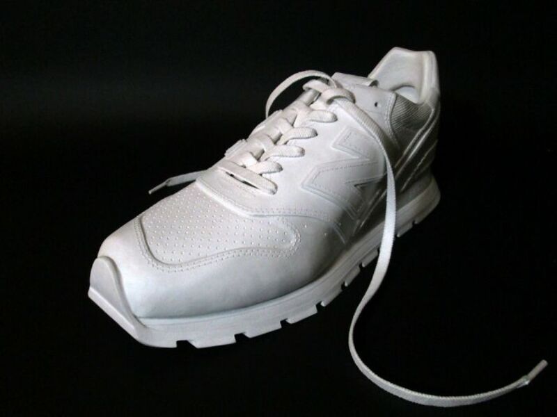 White sneaker with laces on a black background.