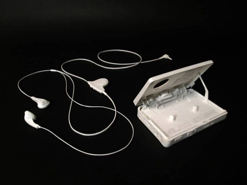 White portable cassette player with white earphones on black background.