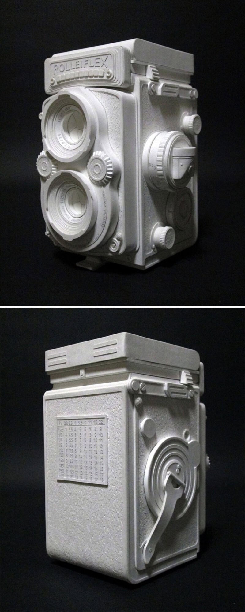 White paper sculpture of a vintage camera and a washing machine.