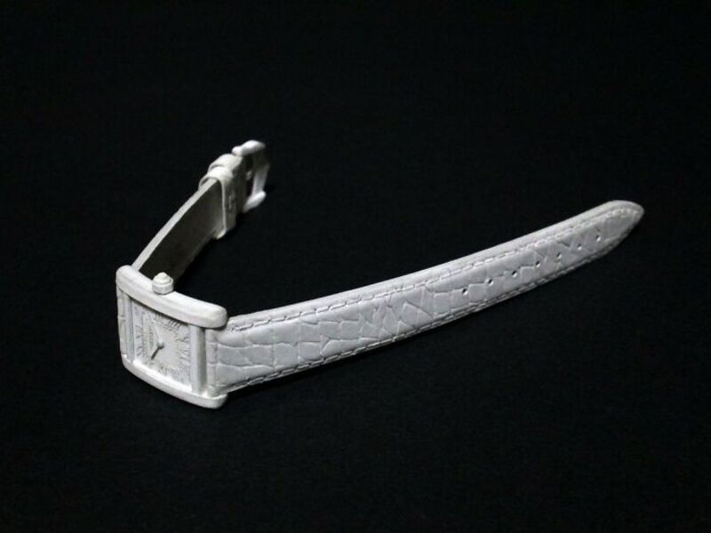 White paper sculpture of a wristwatch with a textured band on a black background.