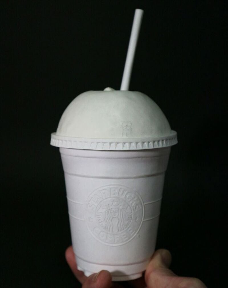 White Starbucks cup with straw against black background.