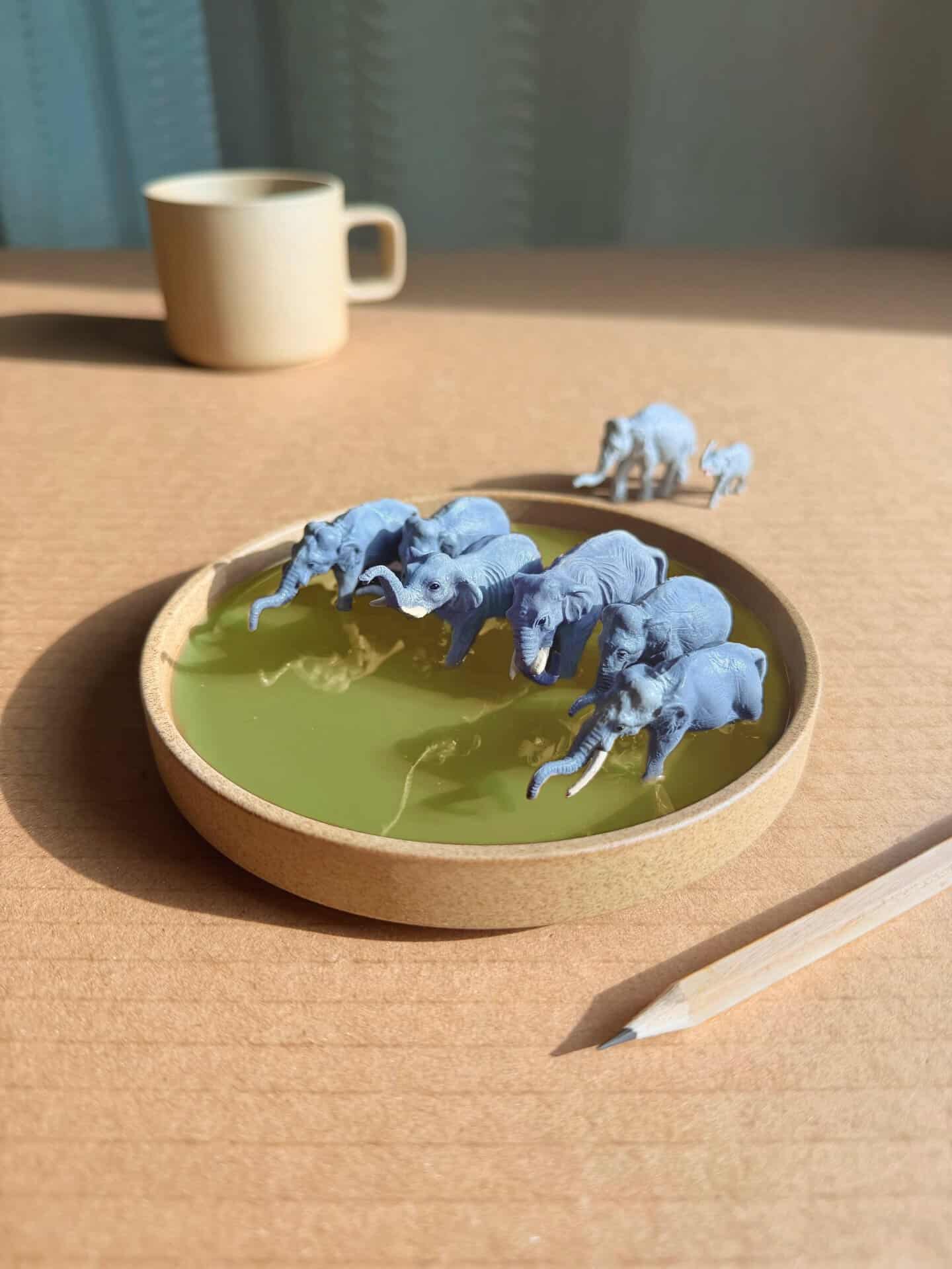 Miniature elephants in a green liquid with a small elephant figure nearby.