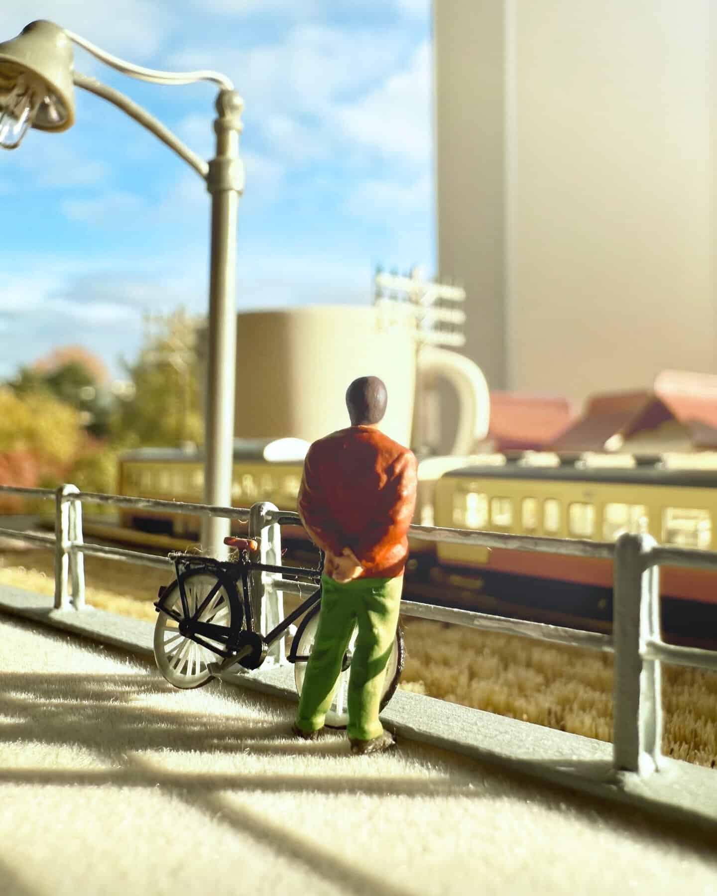 Miniature figure of a man in orange jacket and green pants looking at a model cityscape.