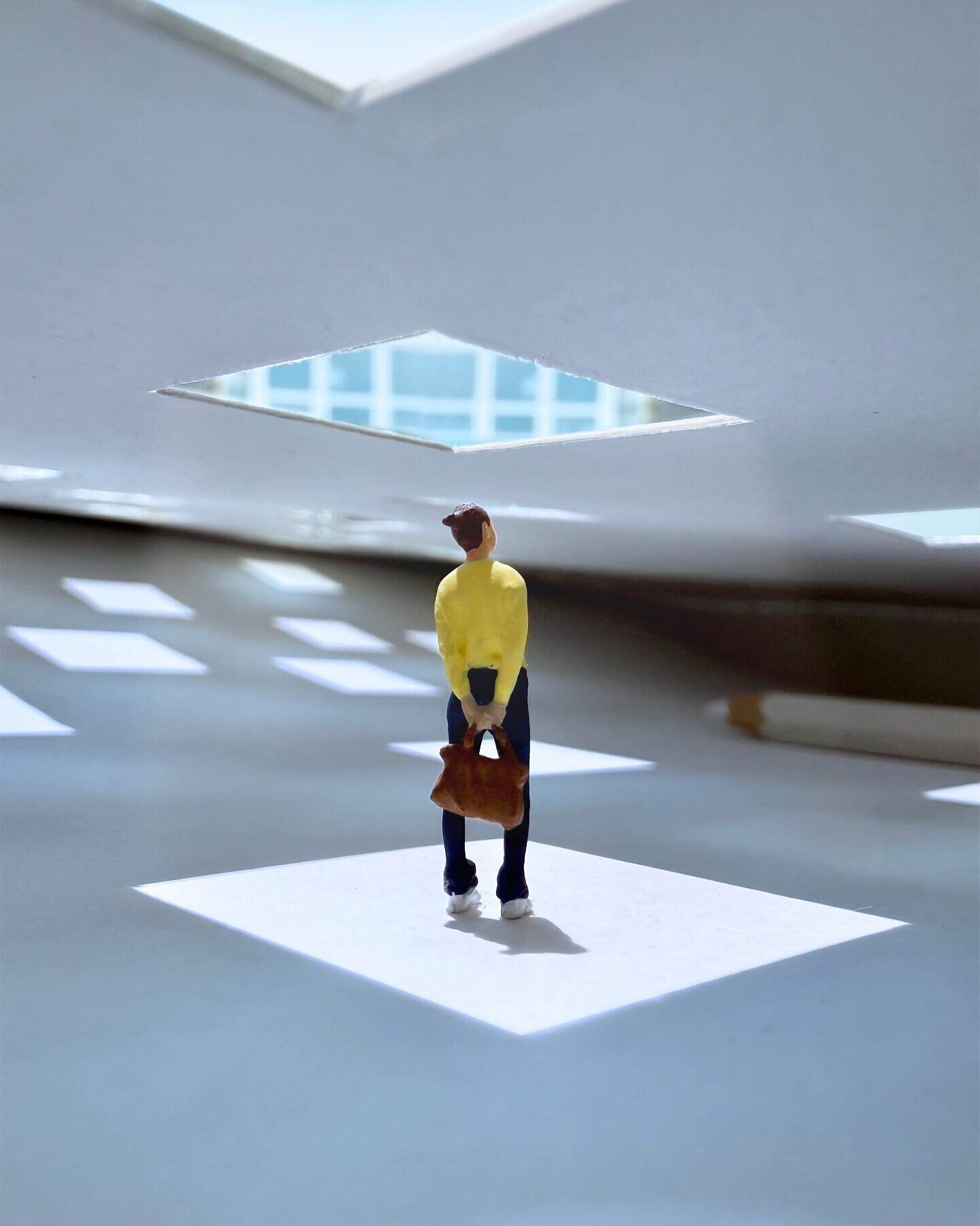 Person standing in a modern, abstract architectural space with geometric openings.