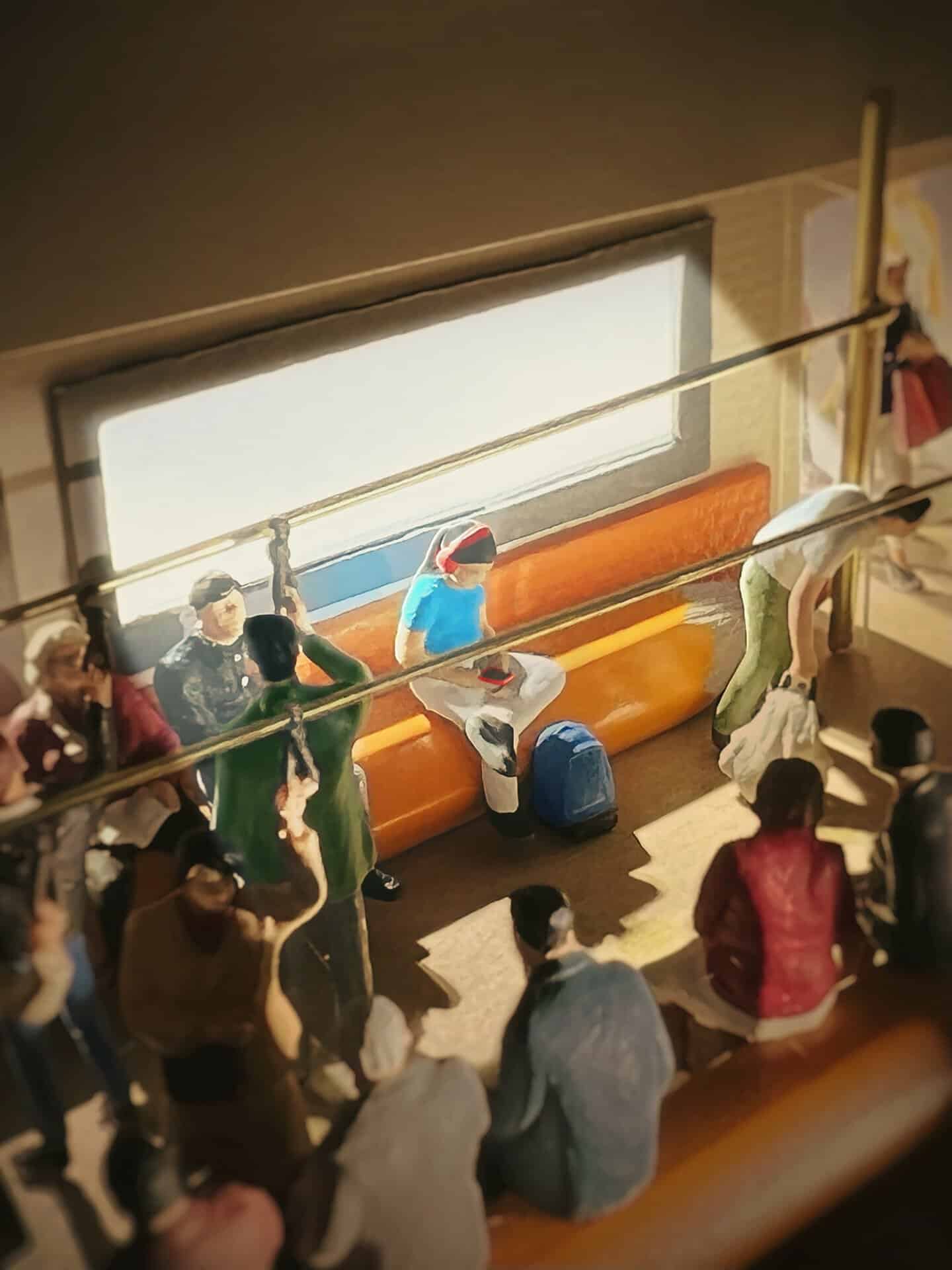 Miniature figures on a bus with a seated figure reading a book by a window.