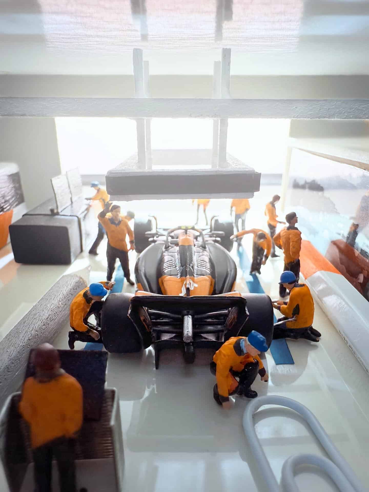 Miniature figures working on a detailed model of a Formula 1 car in a diorama.