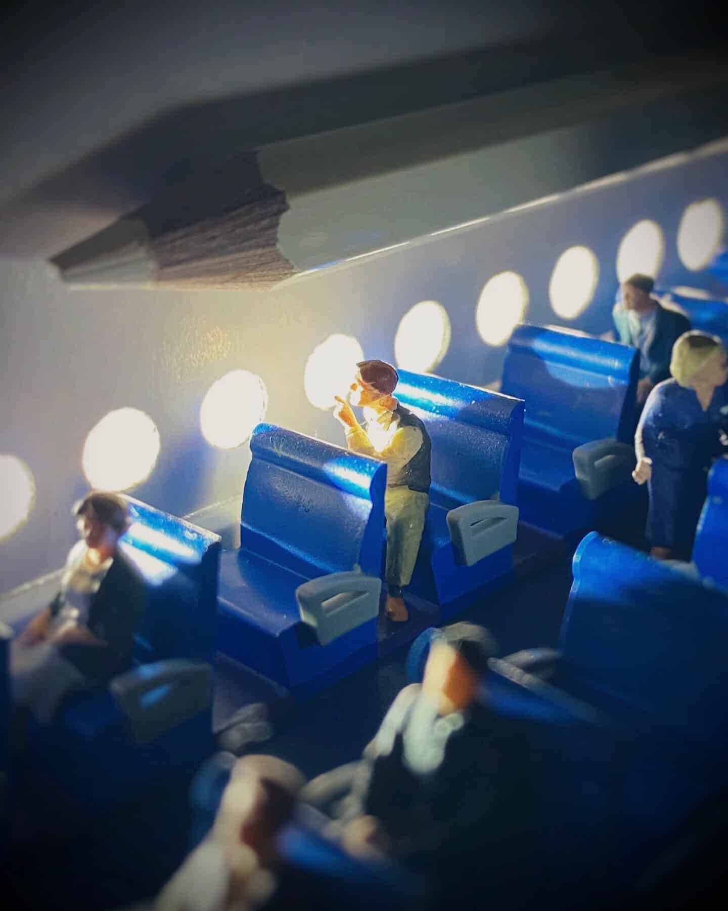 Miniature figures on an airplane, with seats and windows, creating a diorama scene.