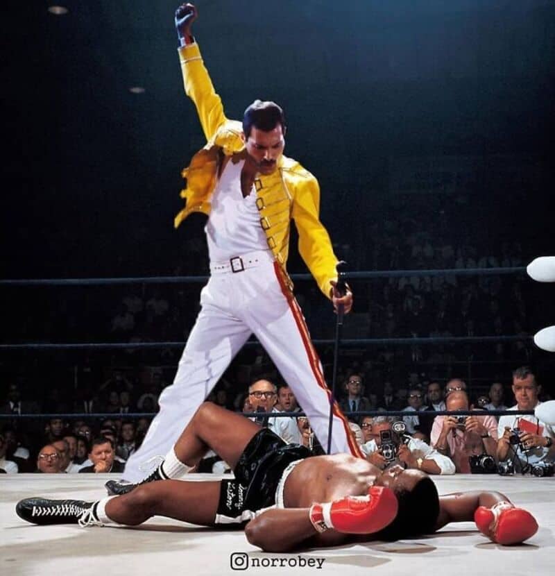 A man in a yellow jacket and white pants stands over a fallen boxer in a ring.