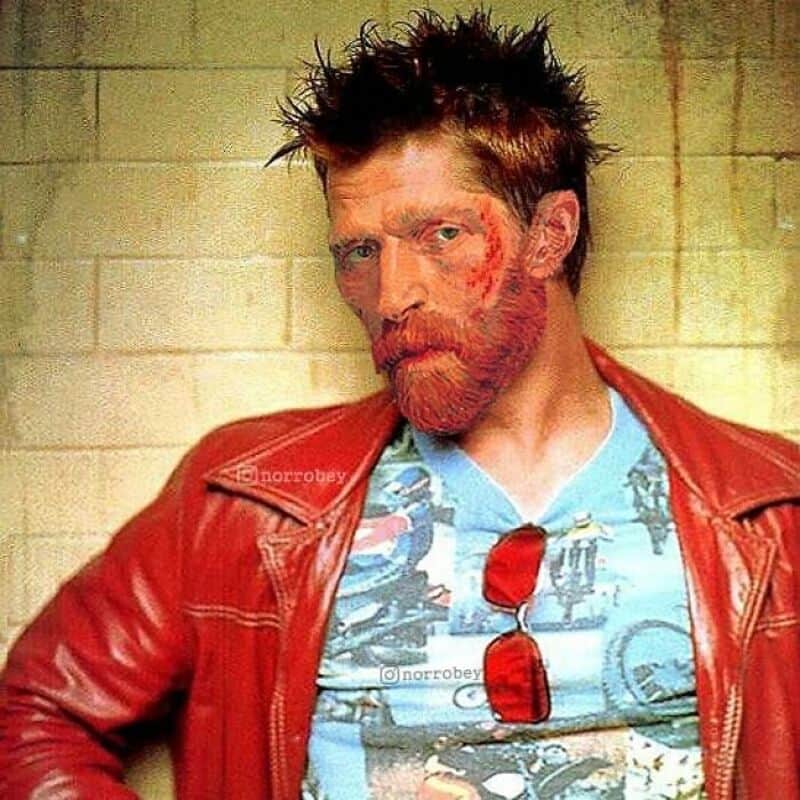 A man with spiky hair and a beard wearing a red leather jacket and a graphic t-shirt.