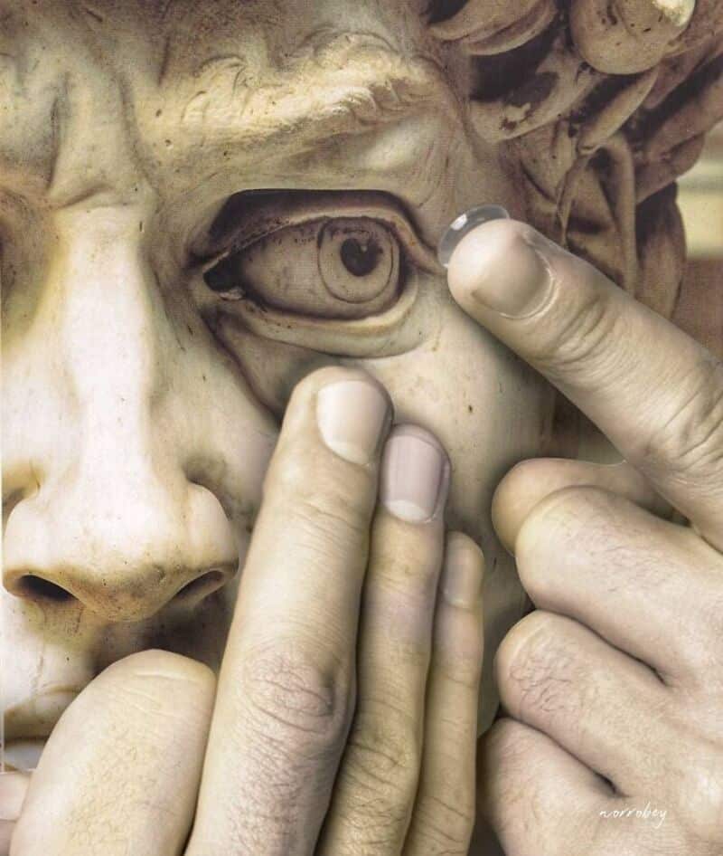 Person touching the eye of a classical marble sculpture with fingers.
