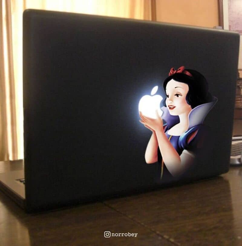 Snow White holding the Apple logo on a laptop with a dark background.