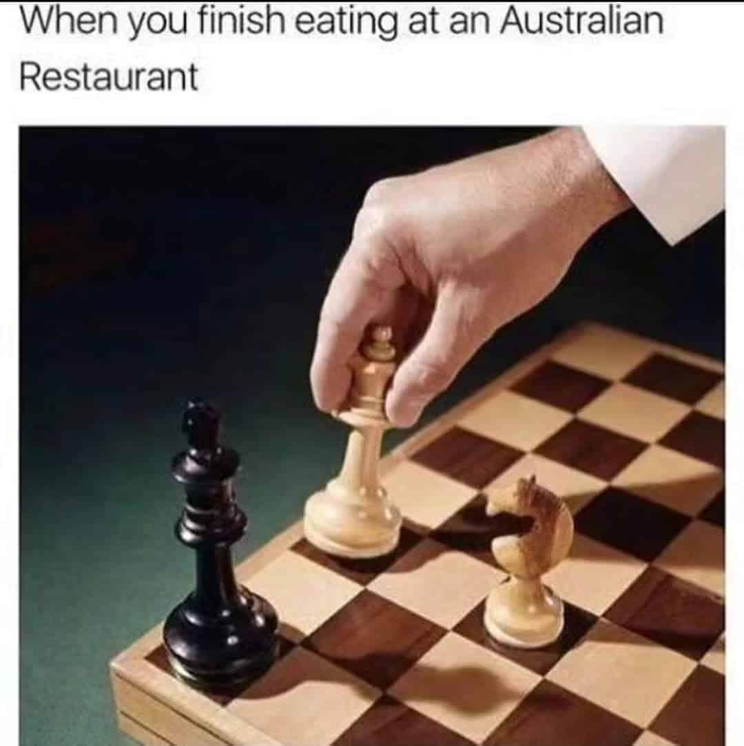 Hand moving a white king on a chessboard after a meal at an Australian restaurant.