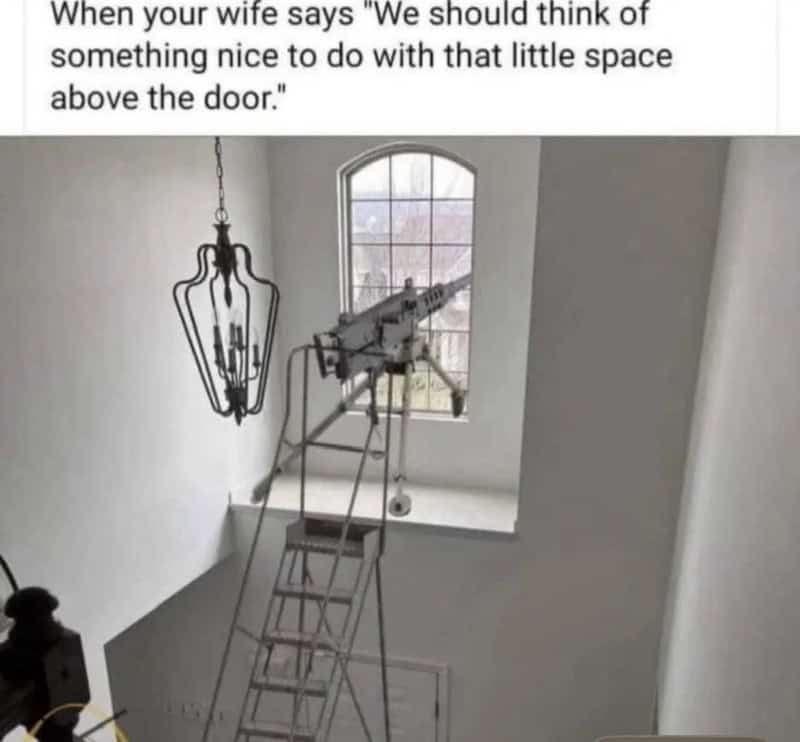 A telescope is set up on a ladder in front of a window in a white room.