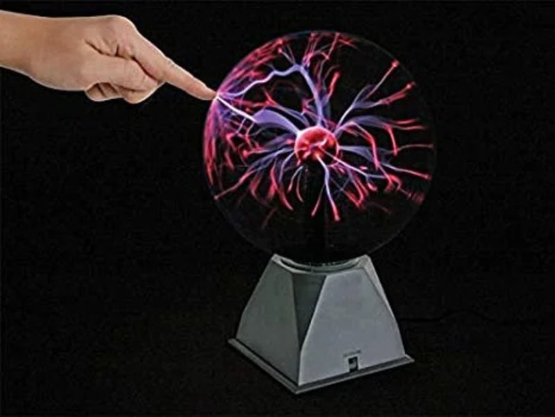 Person's finger points at plasma ball with colorful electric discharges.