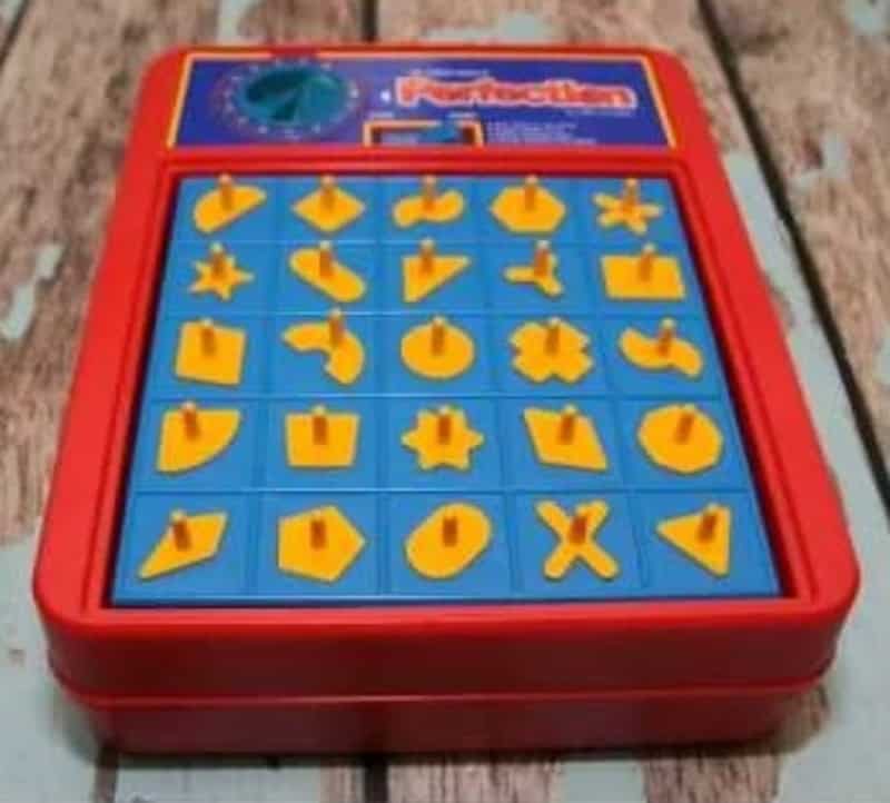 Vintage Guess Who? game with yellow and blue pieces on a wooden surface.