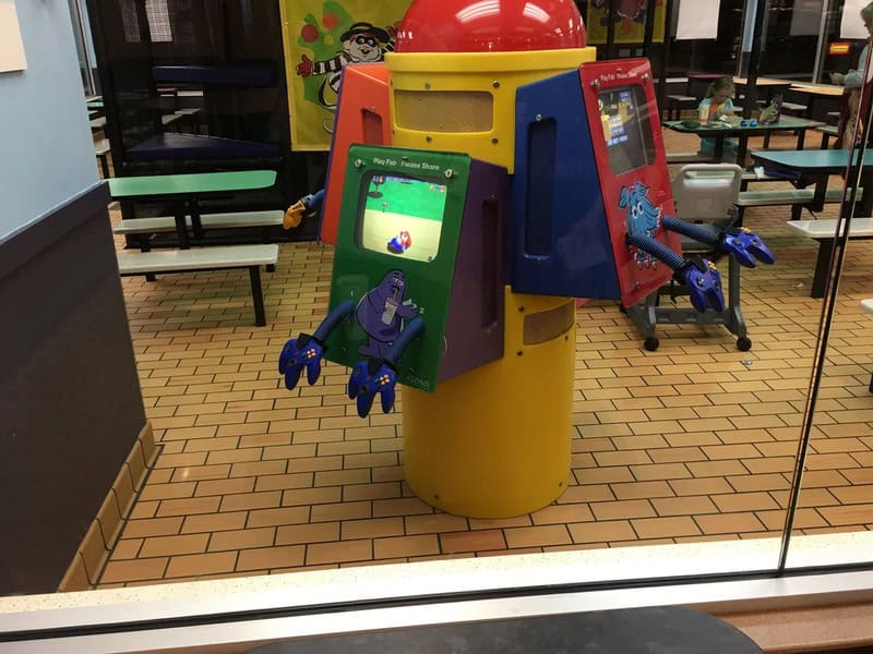 Arcade game machines with colorful screens and controllers in a fast food restaurant.