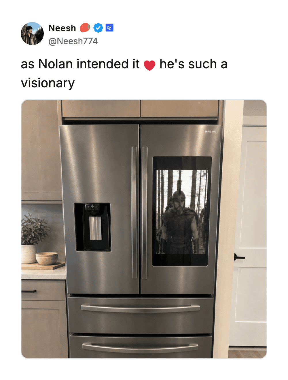 Refrigerator with a reflective glass door showing a person taking a photo.