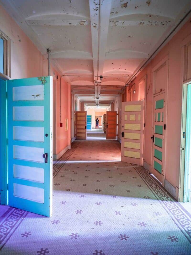 Colorful open doors in a corridor with pink walls and patterned floor.