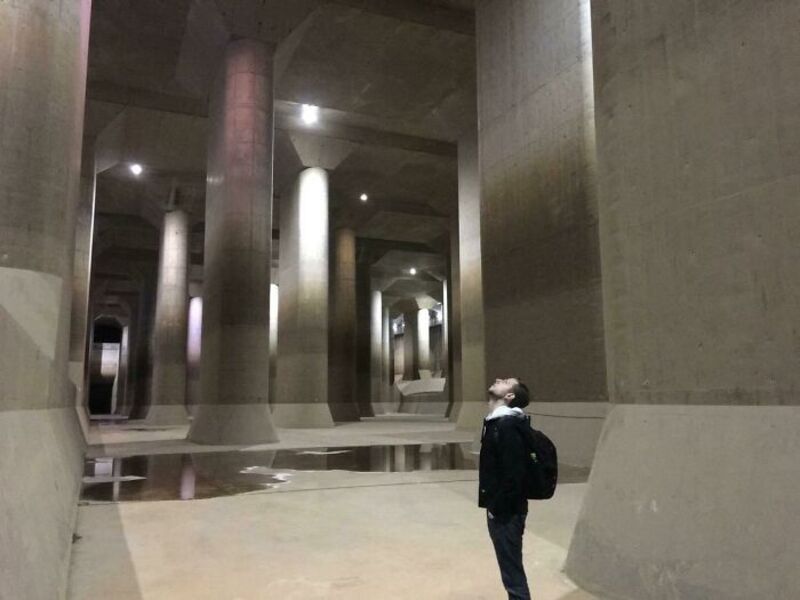 Person standing under large concrete pillars in an underground space.