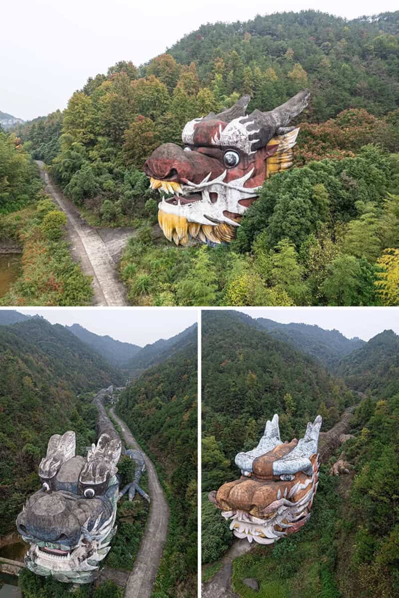 Large dragon head sculpture on hillside, colorful and detailed, surrounded by trees.