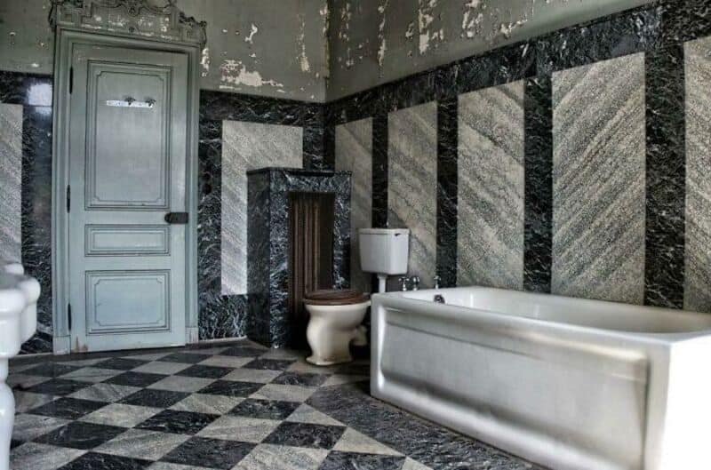 Abandoned bathroom with a bathtub, toilet, and peeling walls.