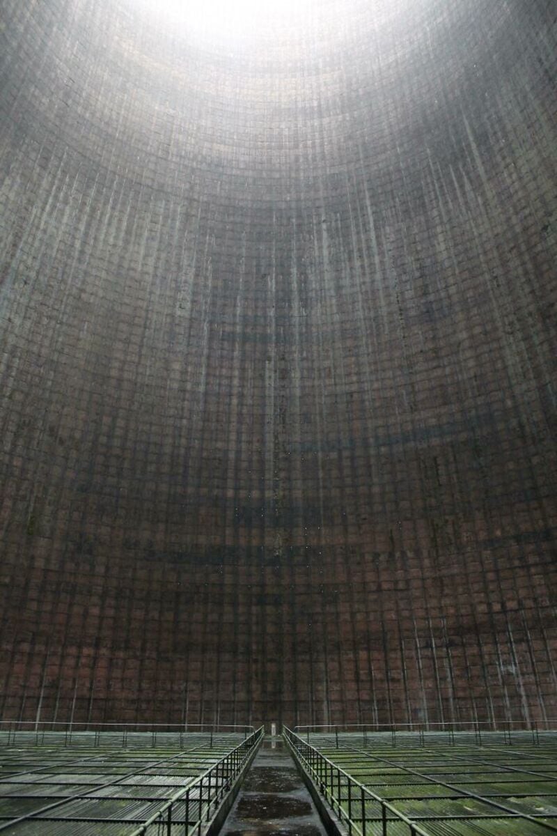 Inside a large cooling tower with a grid pattern and a bright opening at the top.