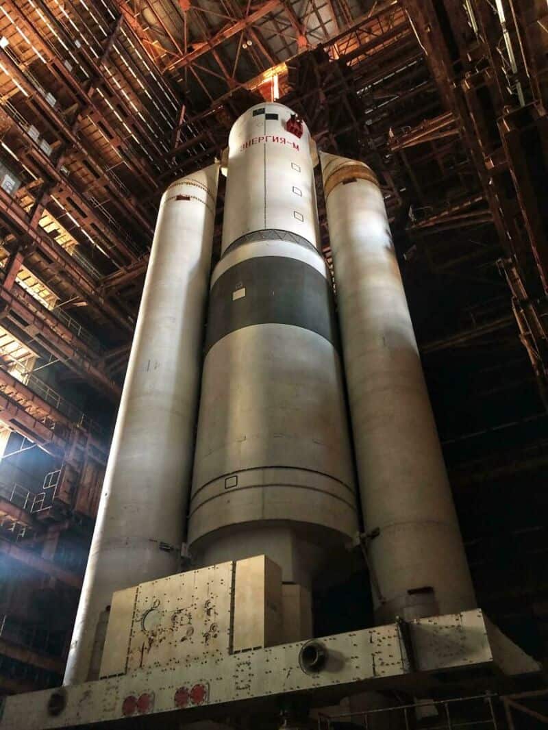 Large rocket inside an industrial building with metal framework and lighting.