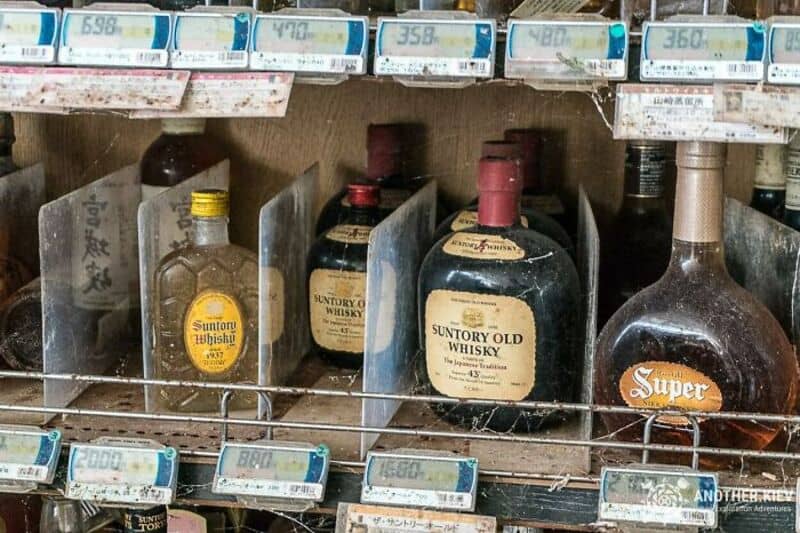 Old bottles of whisky on a shelf in an abandoned store.