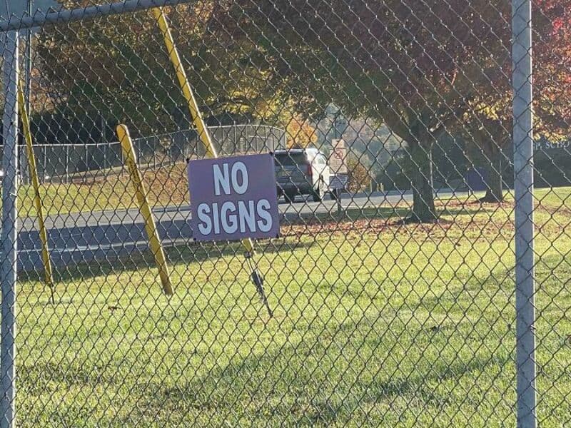 No signs sign on a chain-link fence in a park.