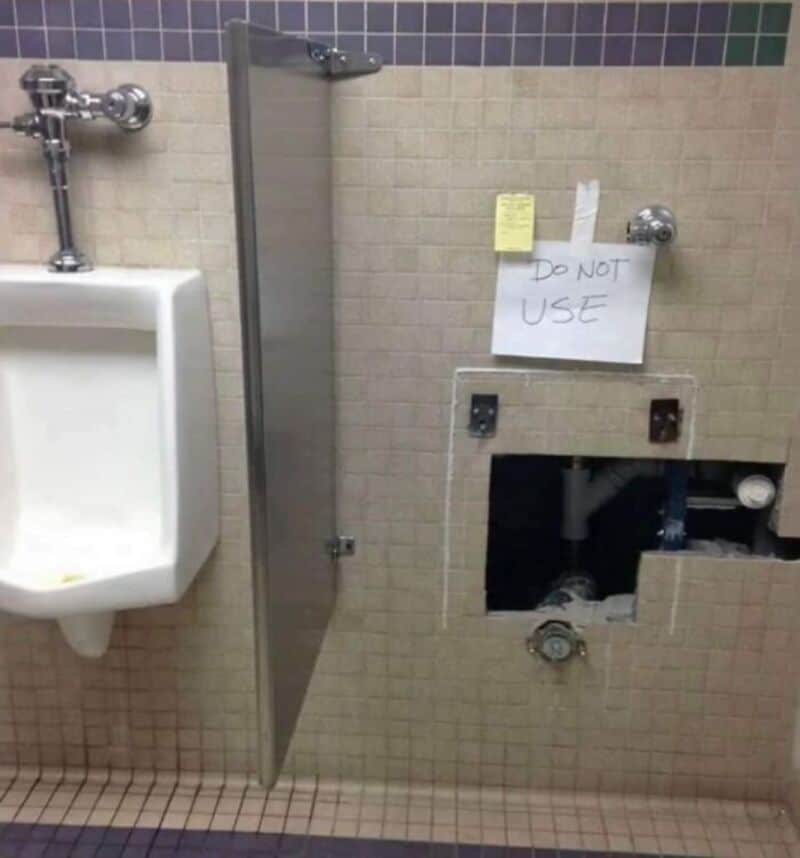 Sign on bathroom wall says 'DO NOT USE' next to a broken toilet.
