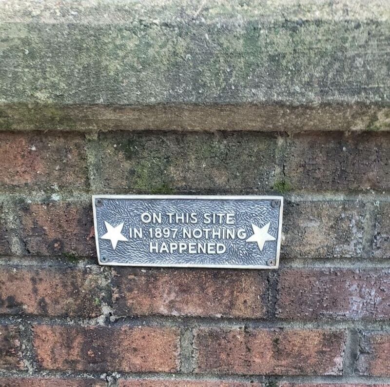 Plaque on brick wall reads: 'On this site in 1897 nothing happened'.