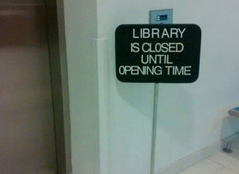 Library is closed until opening time sign in a hallway.