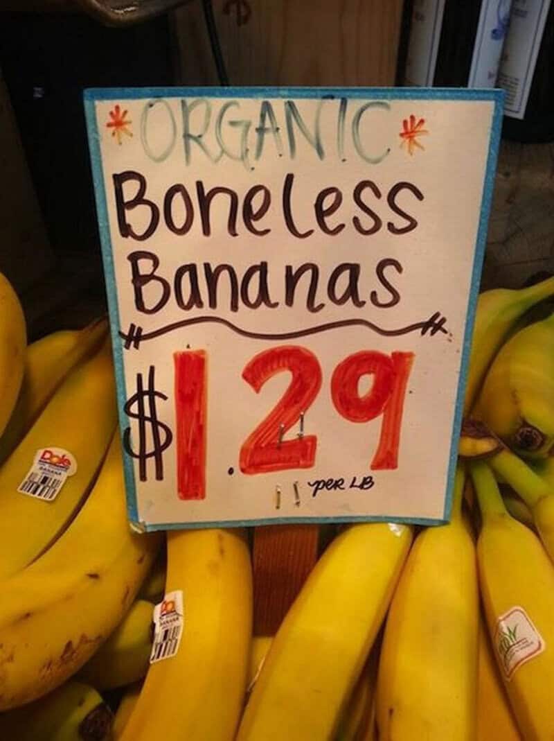 Sign advertising organic boneless bananas for $1.29 per pound with yellow bananas in background.