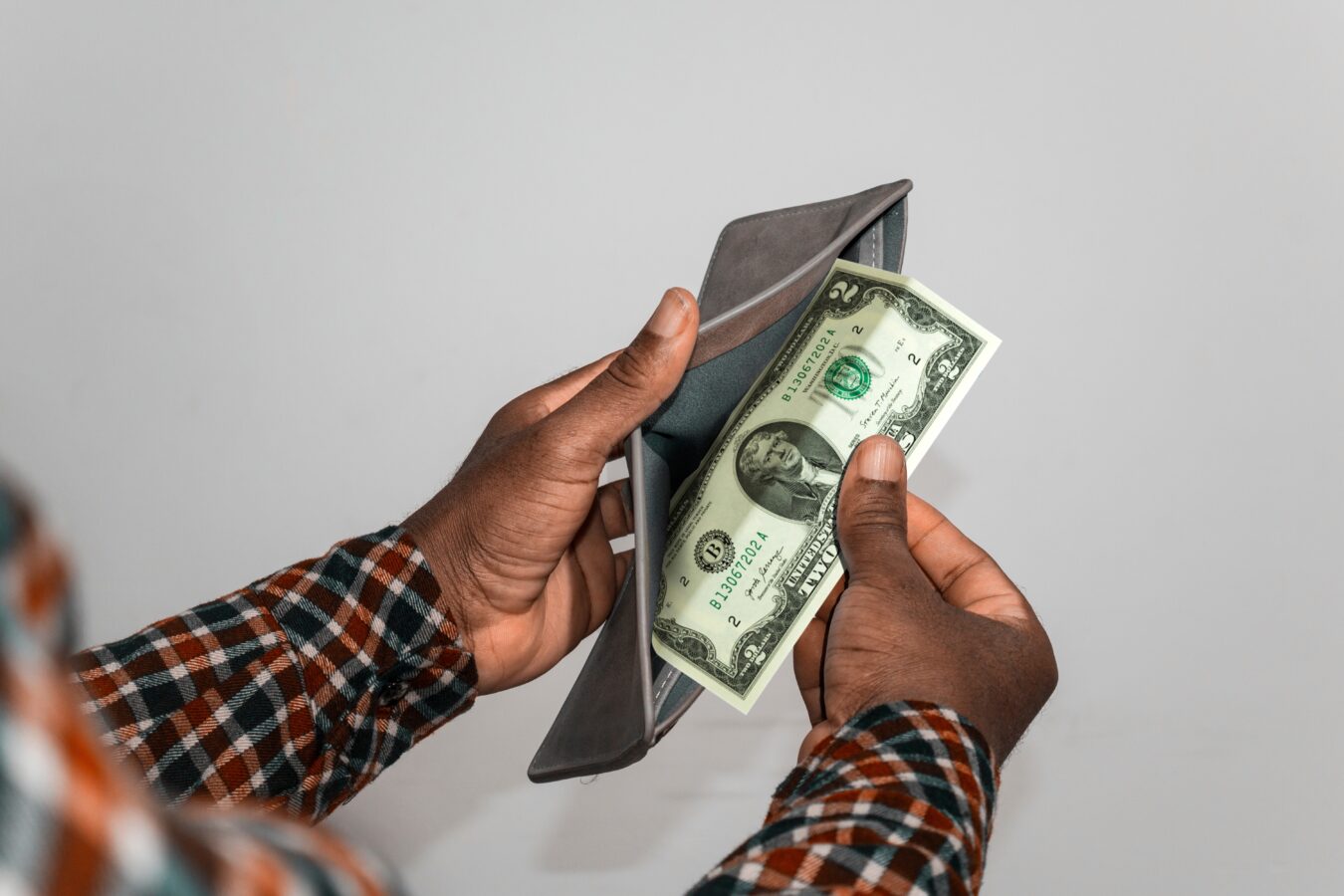 Person holding a wallet with cash and a smartphone.