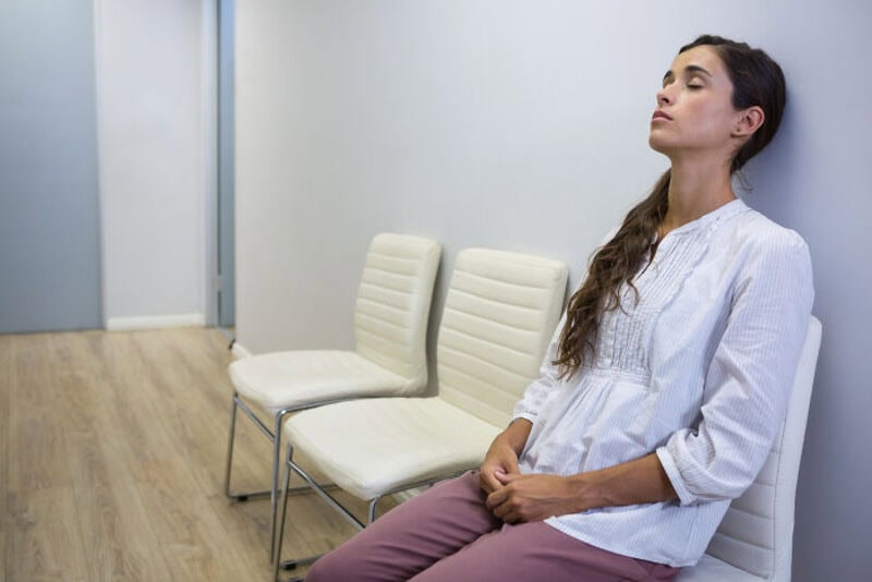 Young woman sitting calmly in a waiting room with closed eyes.