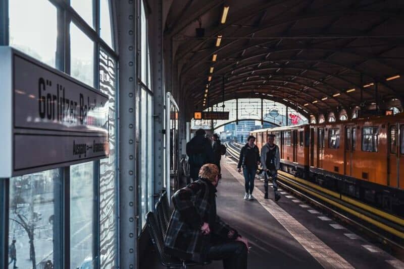 People waiting at a train station with a sign reading 'Göttingen Bahnhof'.