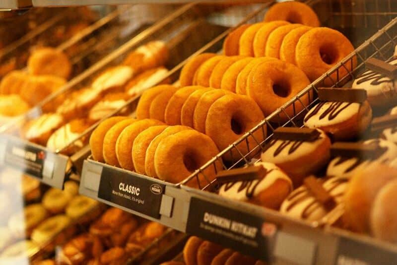 Assorted donuts on display in a bakery, including glazed and chocolate-topped varieties.