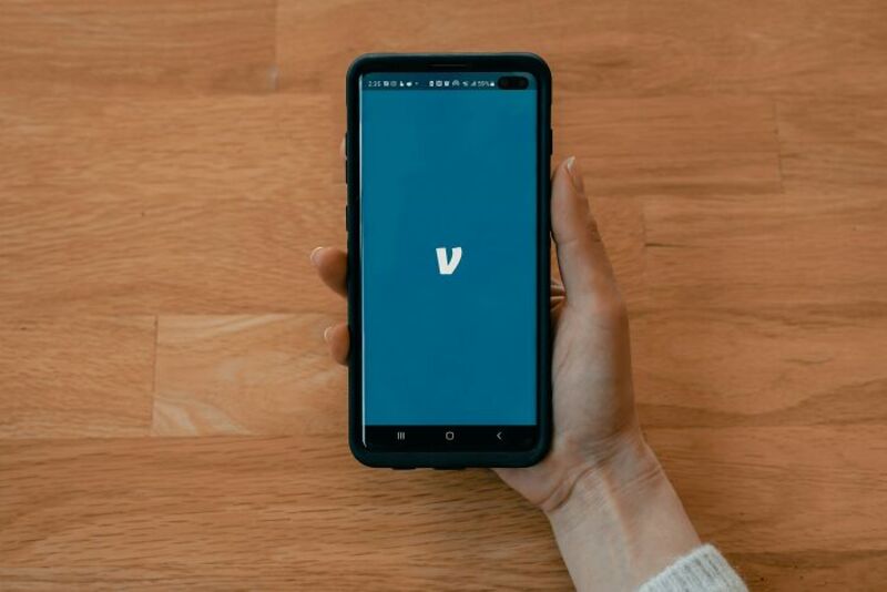 Person holding a smartphone with the Uber app logo on the screen.