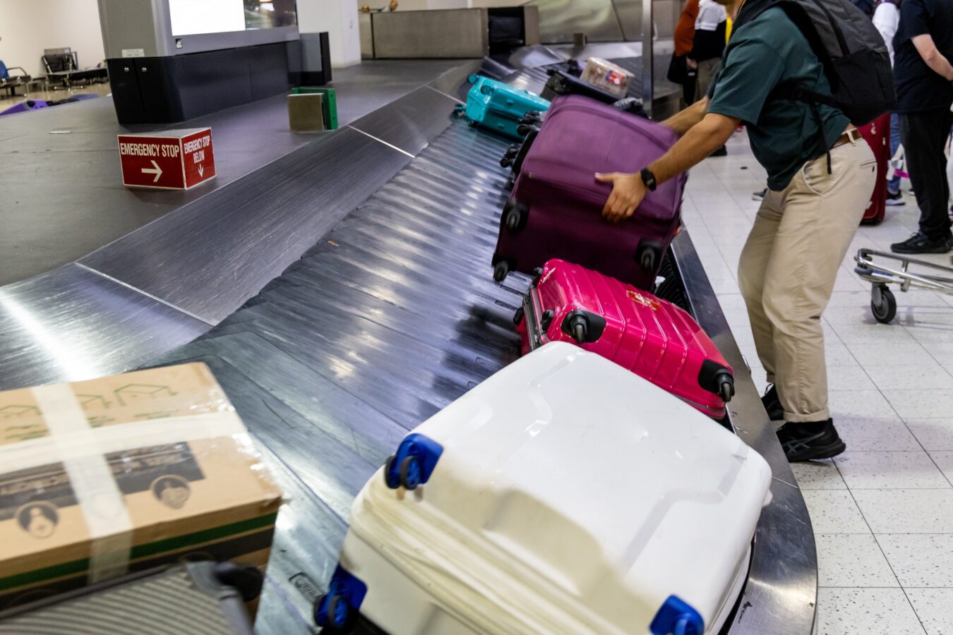 Luggage on baggage carousel at airport with travelers.