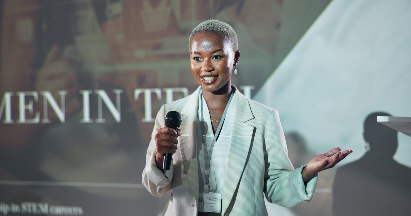 Woman speaking into a microphone at a conference or event.