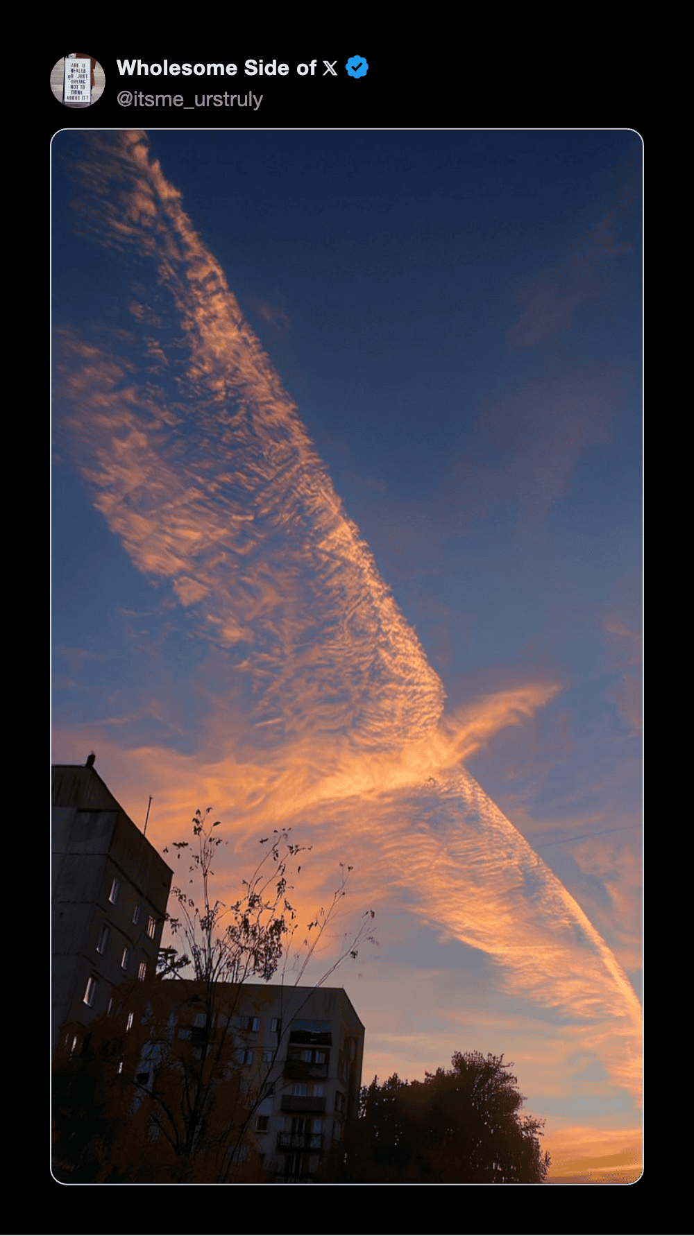 Beautiful sunset sky with orange and blue clouds over city buildings.