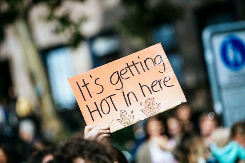 Sign reading 'It's getting HOT in here' held up at a crowd event.