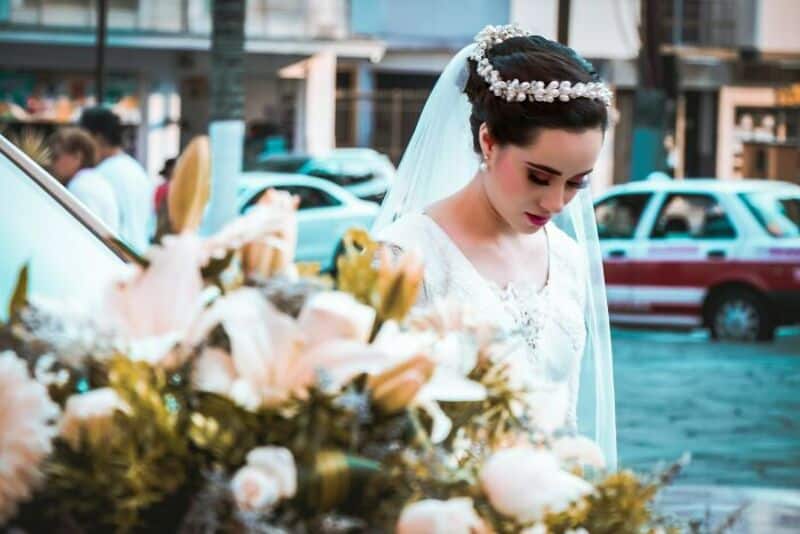 Bride looking down at flowers during her wedding day in an urban setting.