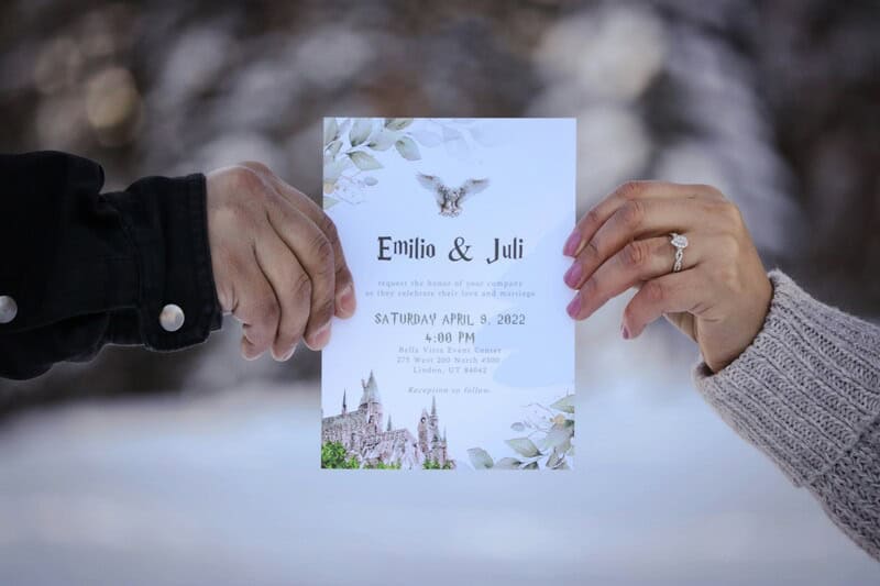 Two hands hold a wedding invitation with a snowy background.